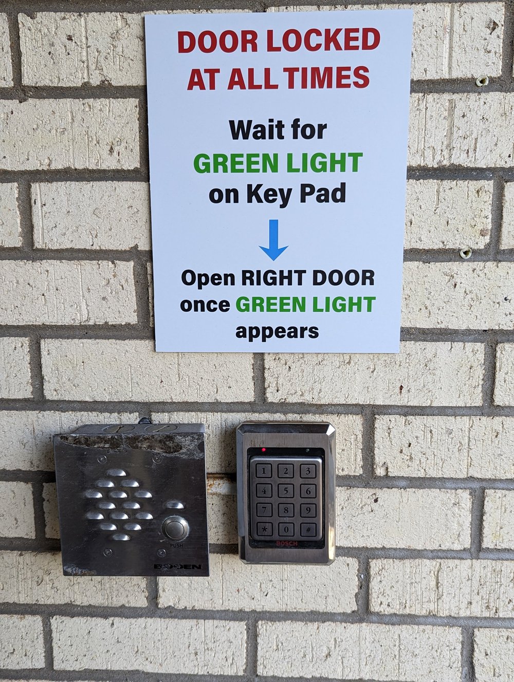 A sign reading Door locked at all times above an intercom with a Push button and a door keypad.