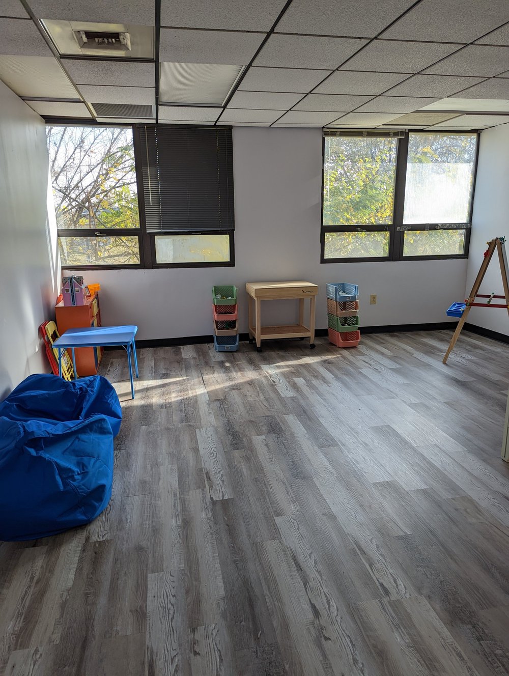 The movement and play room with a bean bag, small table, baskets and an easel.